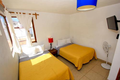 two beds in a room with yellow sheets and a window at Hotel Real Guanajuato in Guanajuato