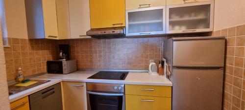 a kitchen with yellow cabinets and a stainless steel refrigerator at Apartman "Cvita" in Drage