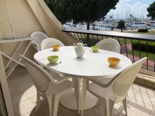 une table blanche et des chaises sur un balcon dans l'établissement Studio 4 pers avec piscine et terrasse, Port Camargue - FR-1-250-167, au Grau-du-Roi