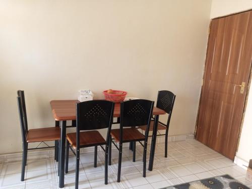 a dining room table with four chairs and a door at FonMark Haven in Webuye