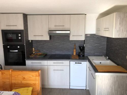 une cuisine avec des armoires blanches et des appareils noirs dans l'établissement Appartement T4 climatisé, 6 couchages, balcon, proche commerces et plage, parking, situé à Port Leucate - FR-1-81-544, à Leucate