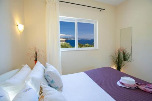 a bedroom with a bed with a window at Villa Thaleia in Sivota