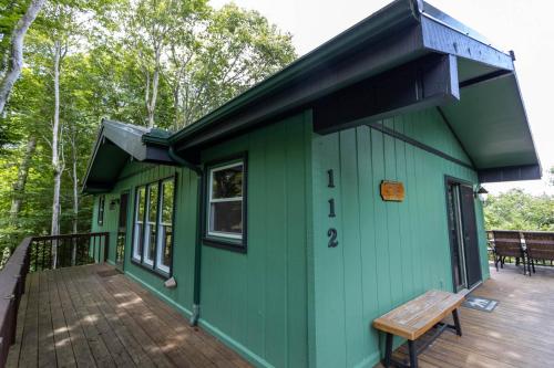 a green cabin with a bench on a deck at Mountain Stay Chalet in Beech Mountain