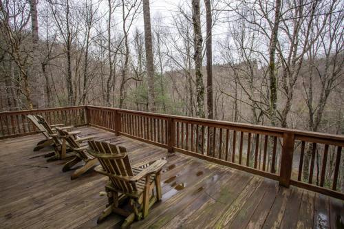 a wooden deck with two chairs and a view of the woods at New River Lure in West Jefferson
