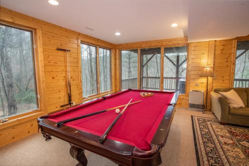 a pool table in a room with wood walls and windows at New River Lure in West Jefferson