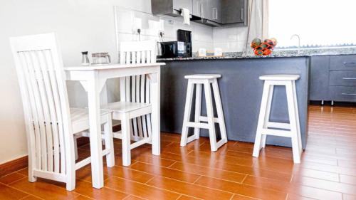 a kitchen with two white bar stools and a counter at Sky Apartment kampala Feel At home in Kampala