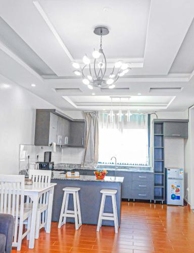 a kitchen with a table and some white stools at Sky Apartment kampala Feel At home in Kampala