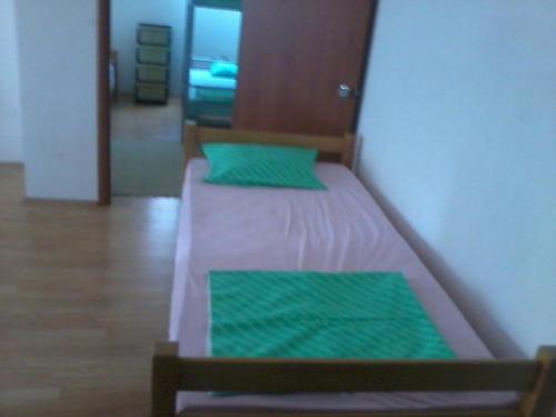 a bed with two green pillows on top of it at BSV Hostel in Skopje