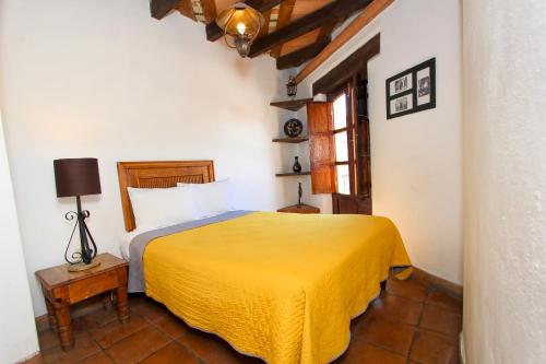 a bedroom with a bed with a yellow blanket at Hotel Real Guanajuato in Guanajuato