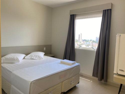 um quarto com uma cama e uma grande janela em San Martin Hotel em Uberlândia
