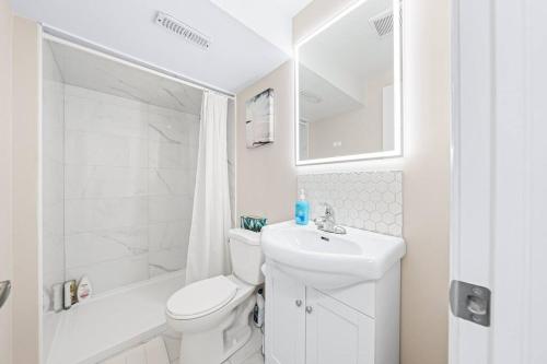 a white bathroom with a toilet and a sink at Adorable 1-bdrm basement, Fast WIFI, Free Parking, Smart TV in Barrie