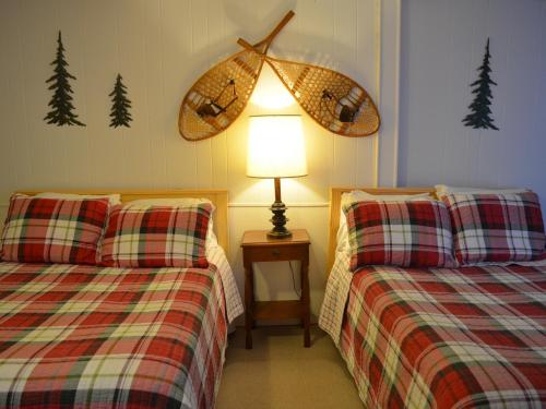 duas camas num quarto com um candeeiro e árvores na parede em The Bavarian Manor Hotel em Purling