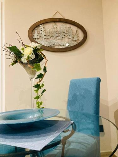 a glass table with a blue chair and a vase of flowers at Cascina Manzo in Dogliani