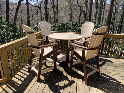 three chairs and a table on a deck at The Escape Cabin in Boone
