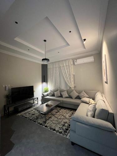 uma sala de estar com um sofá e uma televisão em دخول ذاتي - غرفة نوم وصالة جلوس (هادئة وخصوصية عالية) em As Sayl aş Şaghīr