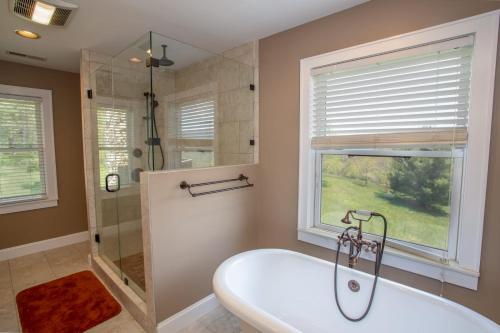 a bathroom with a tub and a shower and a window at The Retreat at Mountain Meadows in Banner Elk