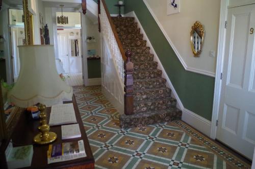 a hallway with a staircase with a table and a lamp at Varley House in Ilfracombe