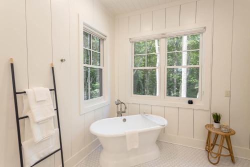 a white bathroom with a tub and two windows at Trouvaille in Blowing Rock