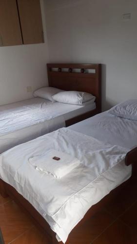 two beds in a room with white sheets at Hotel Gran Girones in Girón