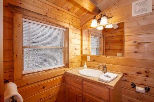 La salle de bains est pourvue d'un lavabo et d'une fenêtre dans une cabane en rondins. dans l'établissement Twin Hollows, à Vilas