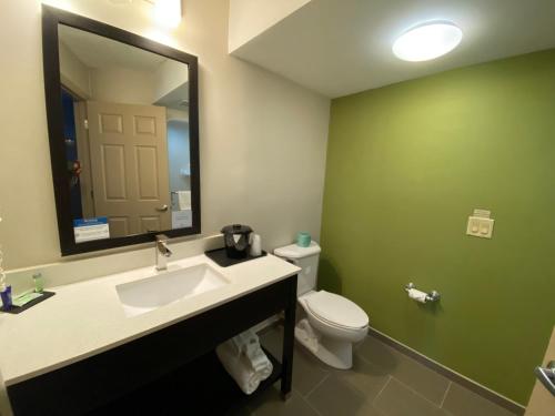 a bathroom with a toilet and a sink and a mirror at Sleep Inn & Suites Niantic North in Niantic