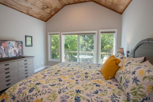 ein Schlafzimmer mit einem Bett und Fenstern sowie einer Kommode in der Unterkunft Vistas at Trout Lake in Blowing Rock
