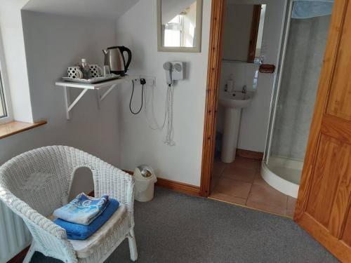 a bathroom with a shower and a chair with a towel at Lurig View B&B Glenariffe in Cushendall