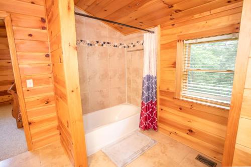 - une salle de bains avec baignoire dans une cabane en rondins dans l'établissement Willow Valley View, à Vilas