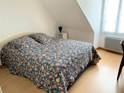 une chambre avec un lit avec un couvre-lit fleuri dans l'établissement Appartement Mansardé avec Garage au Centre de Perros-Guirec - FR-1-368-340, à Perros-Guirec
