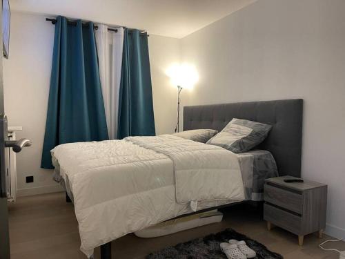 1 dormitorio con 1 cama grande y cortinas azules en Moderne appart JO avec parking, en Saint-Gratien