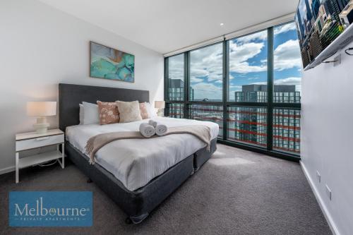 Melbourne Private Apartments - Collins Street Waterfront, Docklands في ملبورن: غرفة نوم بسرير ونافذة كبيرة