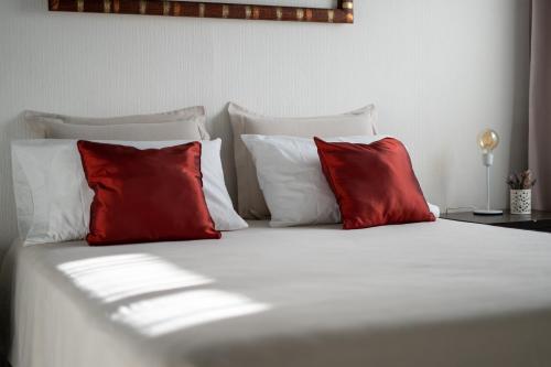 Una cama con tres almohadas rojas. en Amplio, Verde y Privado. en Mendoza