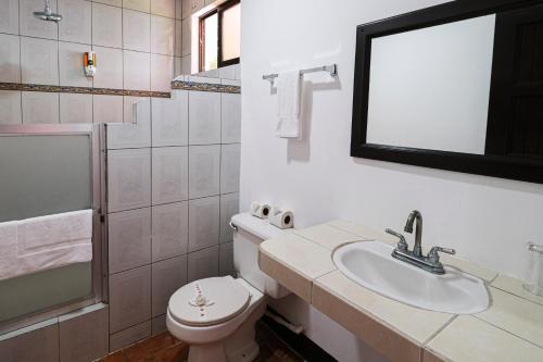 a bathroom with a toilet and a sink and a mirror at Hotel Terraza del Pacifico in Jacó