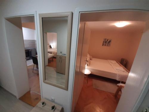 a small room with a bed and a mirror at Haus Apartman Zaječar M&L in Zaječar