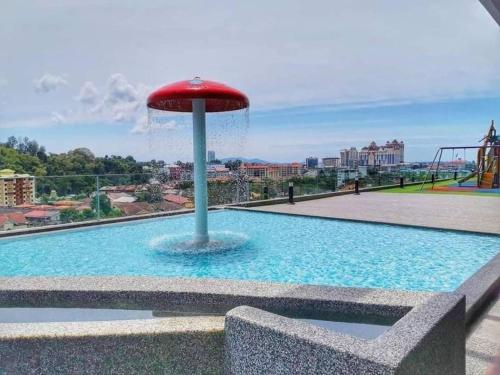 a fountain with a red umbrella in the middle of a pool at Free Netflix&WiFi Putrizarreth Skyhouse Kt Town in Kuala Terengganu