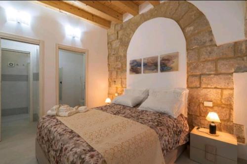 a bedroom with a large bed and a stone wall at LA CASA DEI CANDELAI in Siracusa