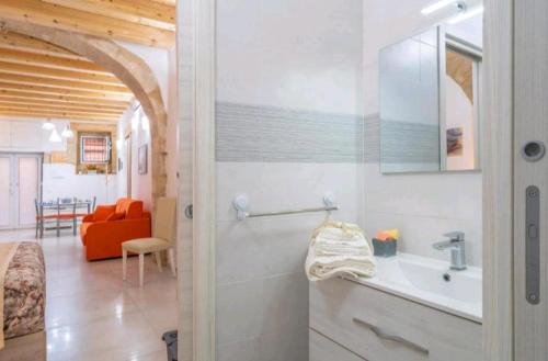 a bathroom with a sink and a room with a couch at LA CASA DEI CANDELAI in Siracusa