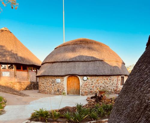 a building with a thatched roof with a door at Kwakunje Guest Lodge in Dundee