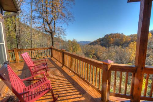 two red chairs sitting on a deck with a view at Blackberry Ridge in Blowing Rock