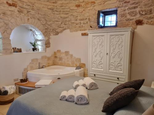 a bedroom with a tub and a bed with towels at Trulli MADIA Luxury Alberobello in Alberobello