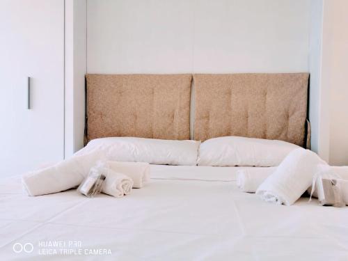 Una cama con sábanas blancas y almohadas. en Casa Gaia, en Golfo Aranci