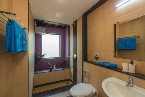 baño con aseo y lavabo y ventana en SaffronStays Courtyard, Nashik - infinity pool villa with a huge party lawn en Nashik