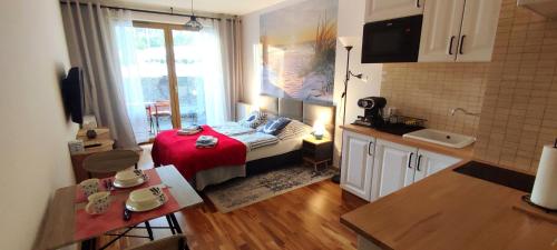 une petite chambre avec un lit avec une couverture rouge dans l'établissement Kawalerka z miejscem parkingowym w hali garażowej, à Sopot