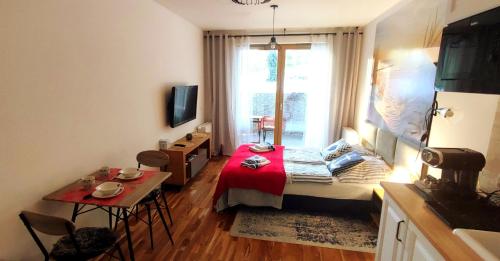 une petite pièce avec un lit et une table dans l'établissement Kawalerka z miejscem parkingowym w hali garażowej, à Sopot