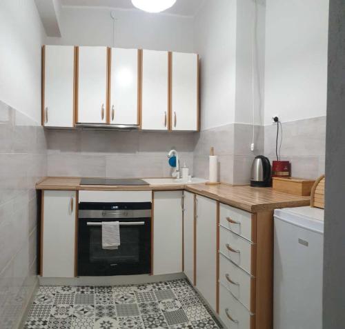 una cocina con armarios blancos y horno negro en APARTAMENT 2+2 en Konin