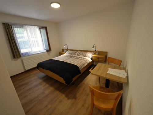 1 dormitorio con cama y mesa de madera con mesa en Bonne Auberge Les Bugnenets, en Le Paquier