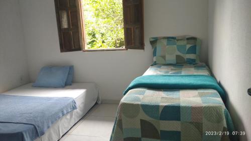 a bedroom with two beds and a window at Chale do vale in Porto Seguro