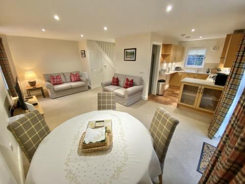 a living room with a table and chairs and a kitchen at Brodie Cottage in Killin