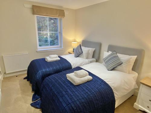 2 letti in una camera da letto con lenzuola bianche e blu di Brodie Cottage a Killin