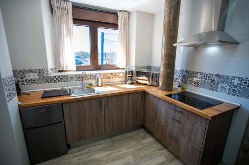 cocina con armarios de madera, fregadero y ventana en La casita del abuelo, en Galizano